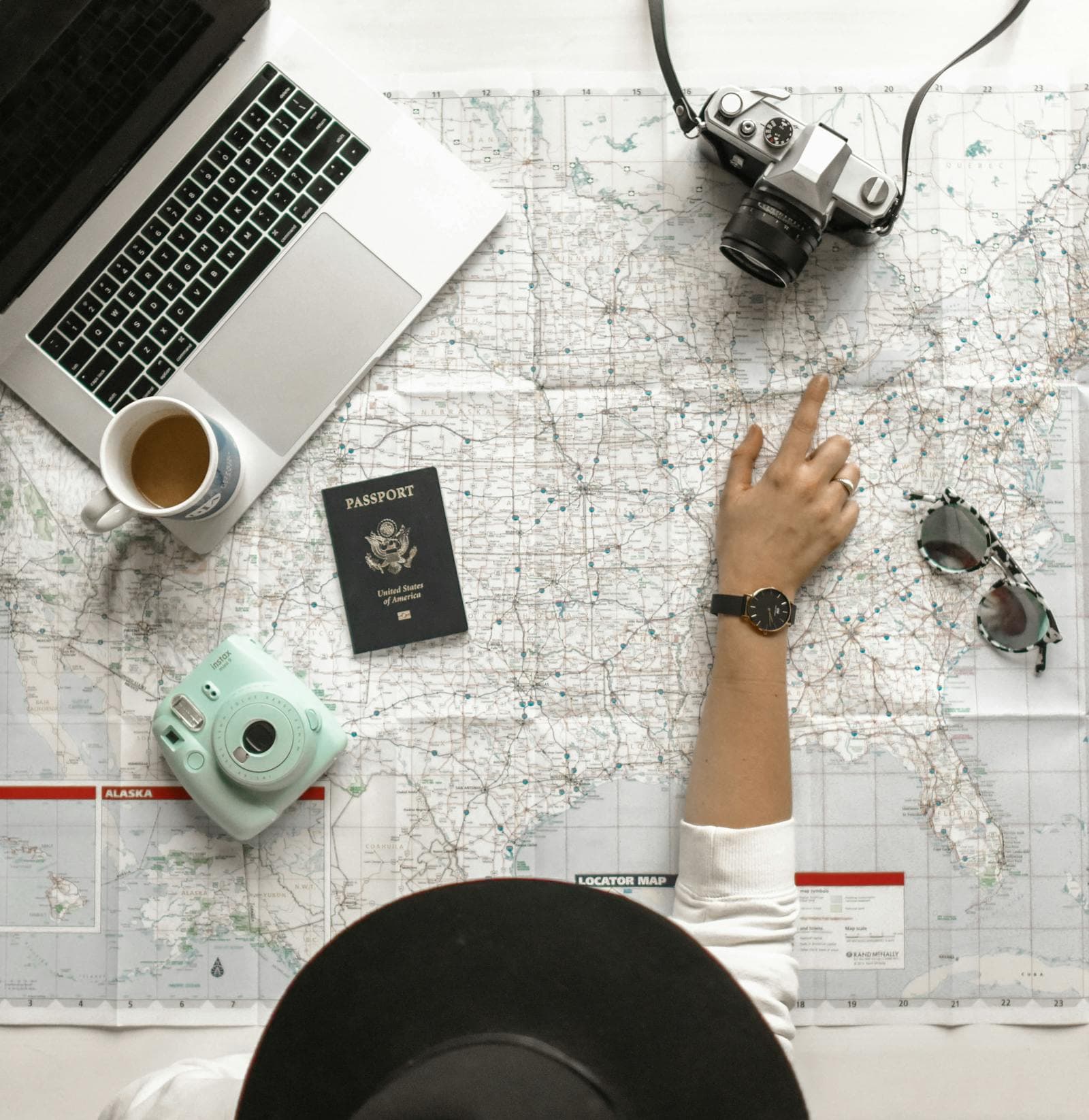 Travel planning desk with a map, laptop, camera, and passport